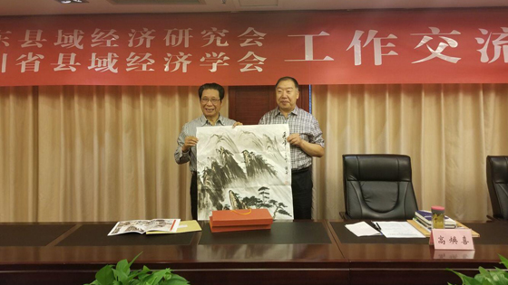 山乐县域经济研究会会长高焕喜向四川省县域经济学会会长张成明赠送书画作品.jpg