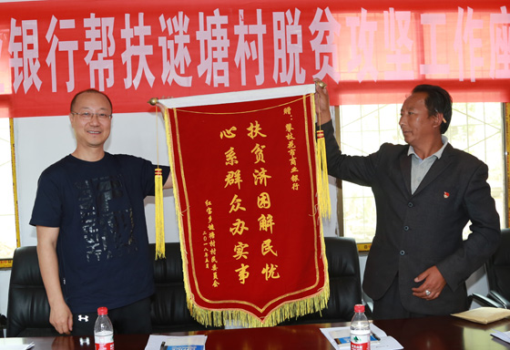 攀枝花市商业银行党组书记、董事长杨宗林（左）接受结对扶贫乡赠送锦旗。.JPG