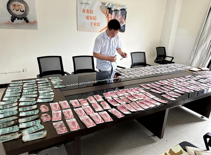 2张场支行组织工作人员在会议室清理晾晒浸湿纸币.png