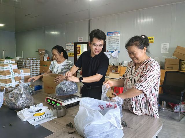 图3  关祖苹正在和村电商中心工人一起称重打包“土货”。潘政吉  摄.jpg